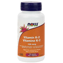 A bottle of NOW Foods Vitamin K-2 100 mcg with 100 Vcaps. The label is primarily white and orange, and it's indicated that the capsules are vegetarian.